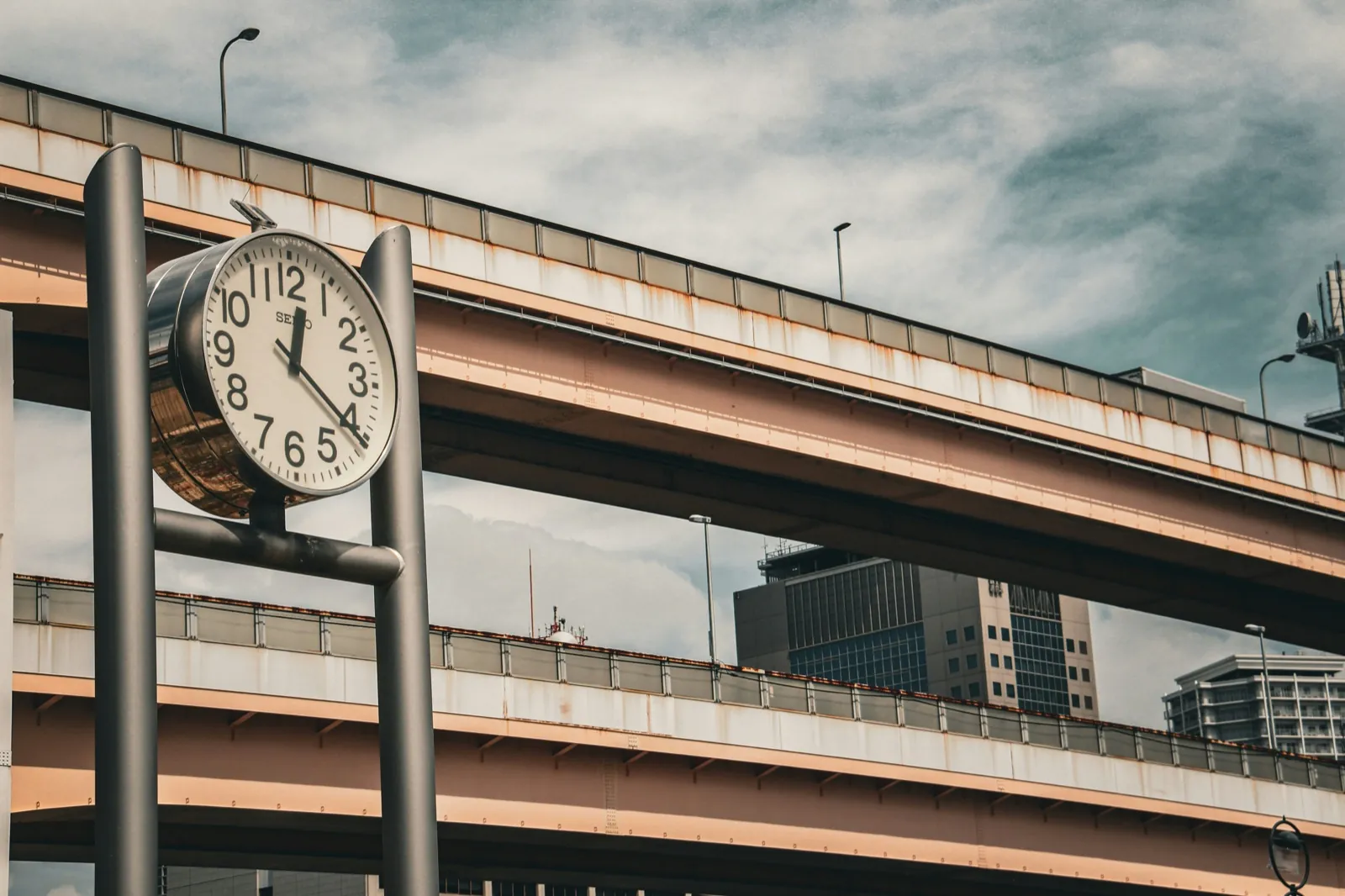 A city clock beside elevated highways — the current local time in Japan